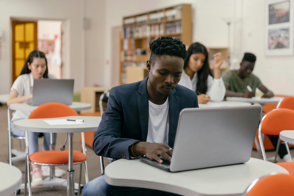A student with a laptop in a classroom setting alongside other learners